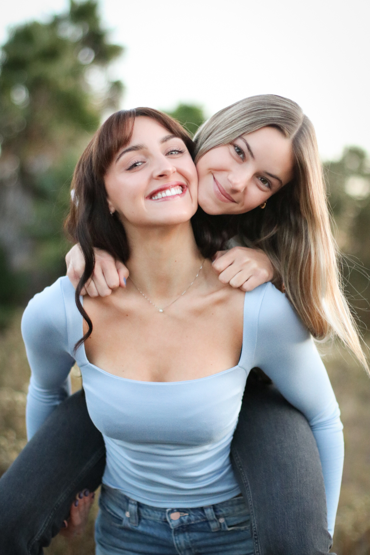 Two sisters laughing together at golden hour