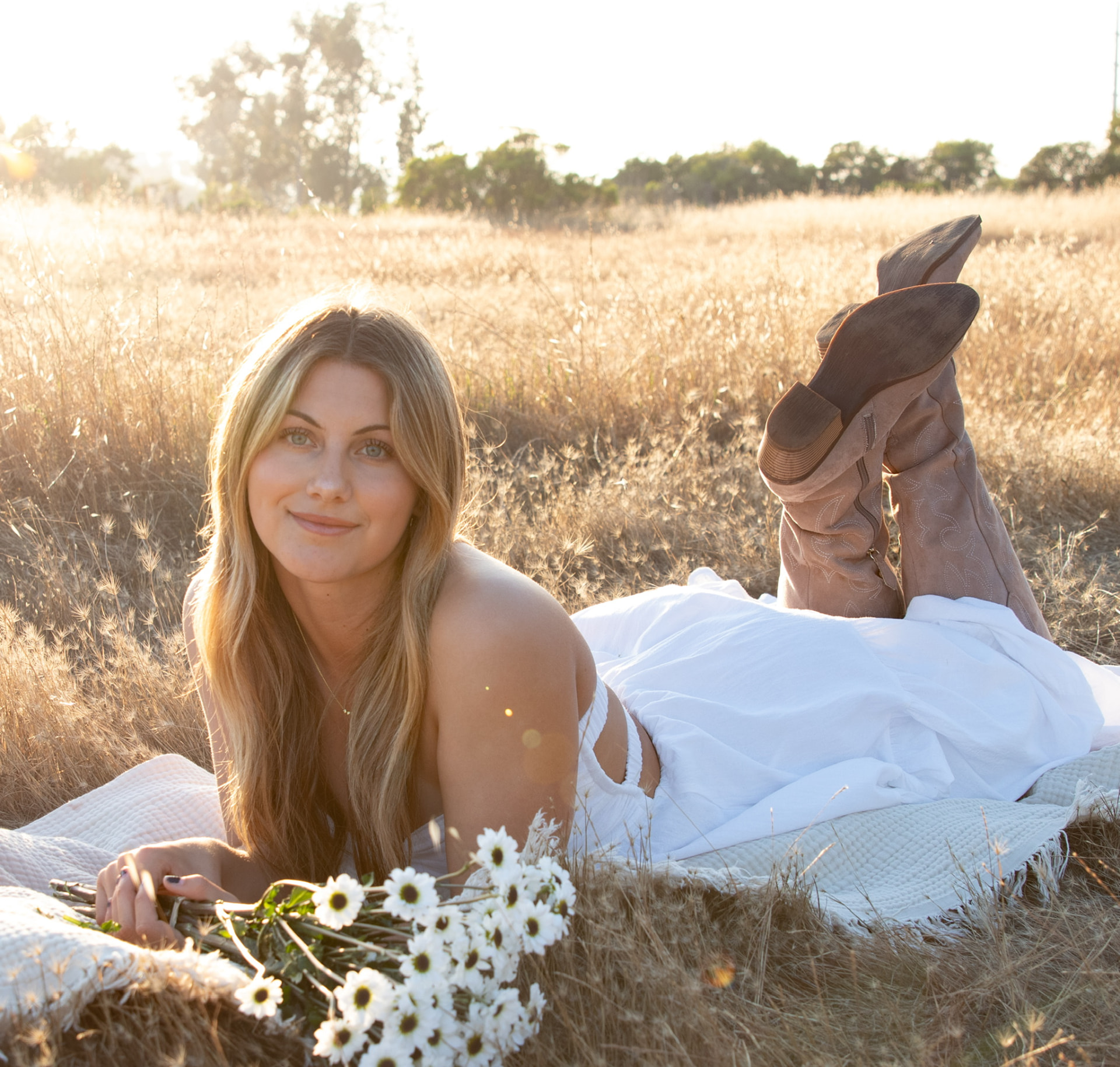 Senior lying on a blanket with daisies in a golden field at sunset
